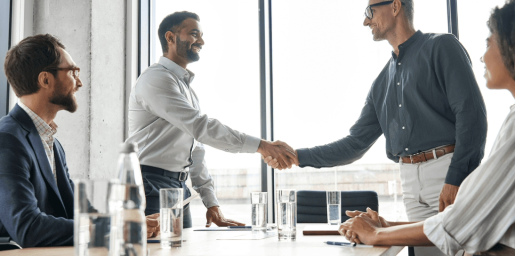 Homens de terno apertando as mãos. Contrato Power Purchase Agreement PPA: Compre energia com preços mais baixos e garanta a sustentabilidade do seu negócio