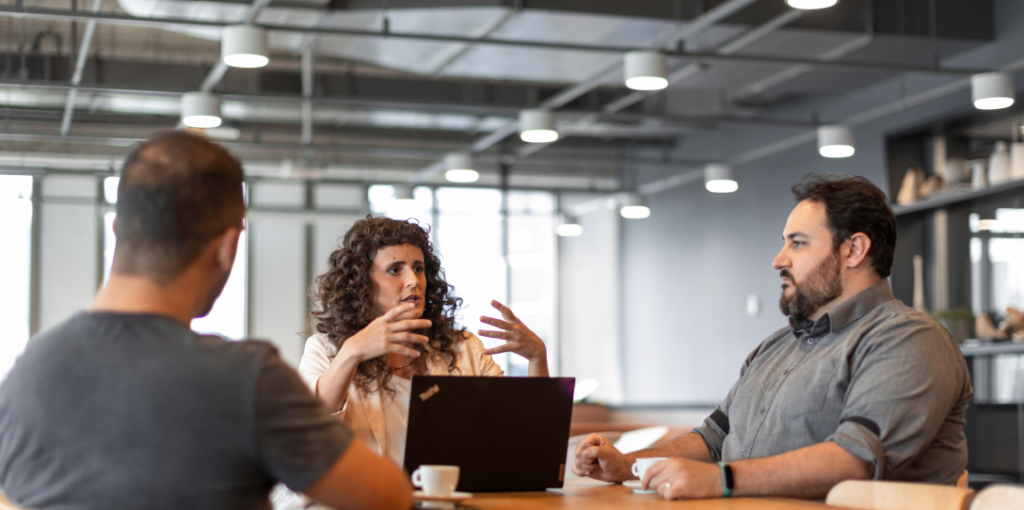 Entenda em profundidade o conceito de governança corporativa, sua finalidade e os benefícios de implementá-la na sua empresa para otimizar a gestão e potencializar resultados. Pessoas conversando em uma mesa de reunião